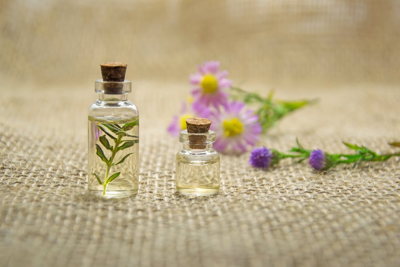 service-02 Glass bottles with essential oils and fresh flowers on burlap fabric creating a natural aroma.